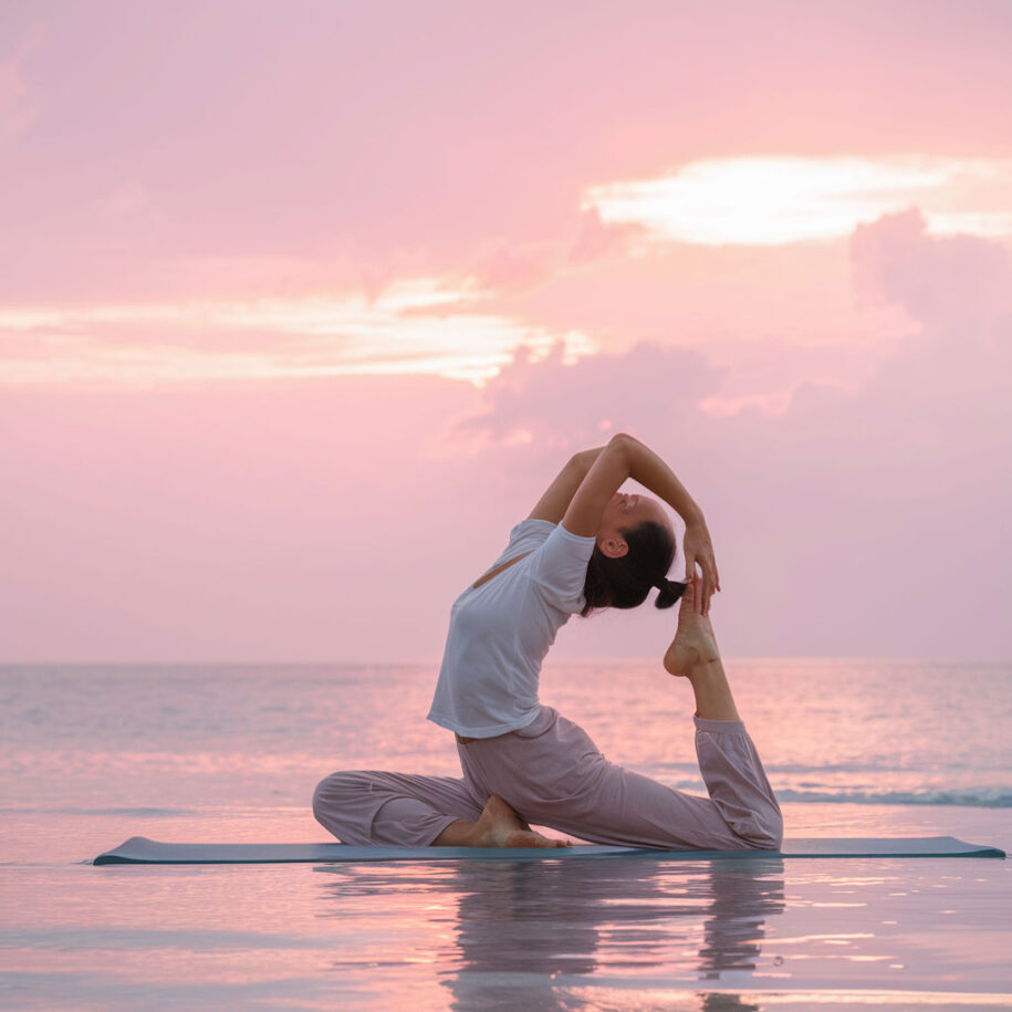 Donna in yoga sulla spiaggia al tramonto